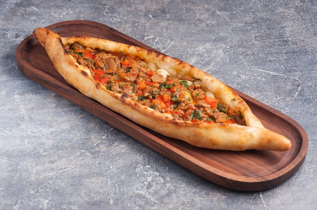 Saborosa pide com carne e legumes em uma tábua de madeira Cozinha turca