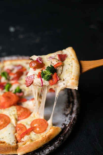 Saborosa pizza fatiada com manjericão folhas na mesa preta