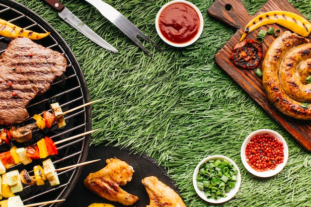 Saborosa refeição com carne grelhada e espeto de kebab no pano de fundo de grama