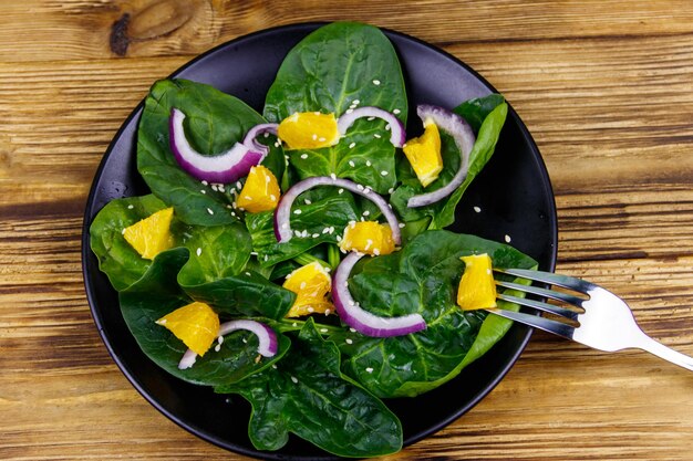 Saborosa salada com espinafre laranja cebola roxa e sementes de gergelim na mesa de madeira Vista superior Comida saudável ou conceito vegetariano