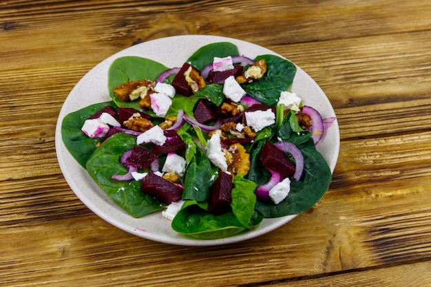 Saborosa salada de espinafre com noz de queijo feta de beterraba cozida e cebola roxa na mesa de madeira Comida vegetariana saudável