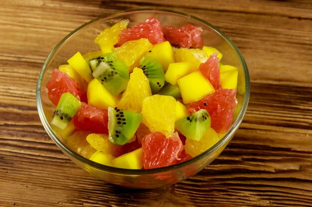 Saborosa salada de frutas em tigela de vidro na mesa de madeira