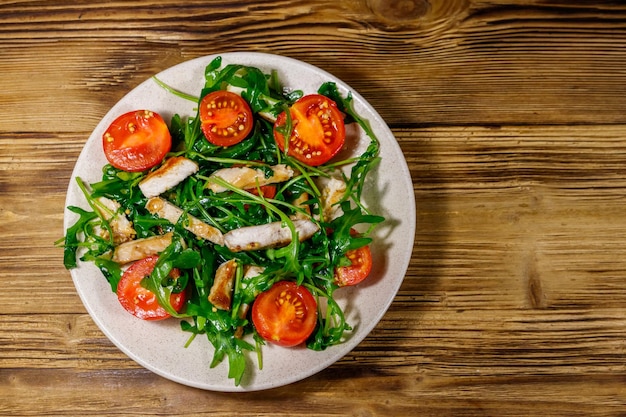 Saborosa salada de peito de frango frito rúcula fresca e tomate cereja na mesa de madeira Vista superior