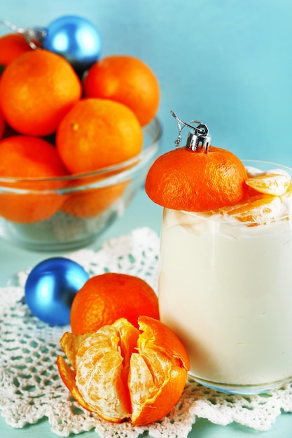 Saborosa sobremesa de leite com pedaços de tangerina fresca em tigela de vidro, na cor de fundo de madeira
