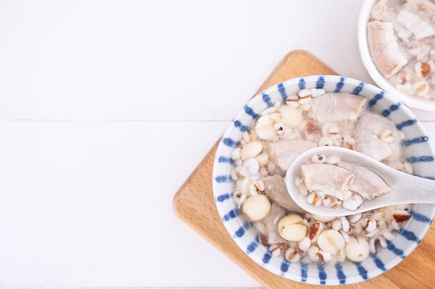 Saborosa sopa de sabor de ervas de quatro tônicos, comida tradicional taiwanesa com ervas, intestinos de porco na mesa de madeira branca, close-up, plano leigo, vista de cima.