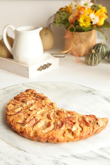 Saborosa torta de maçã recém-assada com maçãs e uma xícara de chá no fundo. conceito de comida saudável caseira.