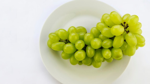 saborosa uva verde fresca em uma tigela e sobre fundo branco