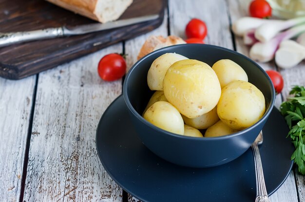 Saborosas batatas cozidas com endro, esparsa e cebola em uma tigela preta