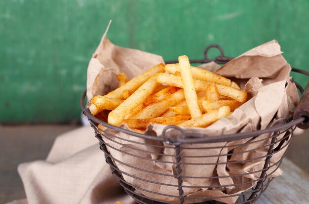 Saborosas batatas fritas na cesta de metal na mesa