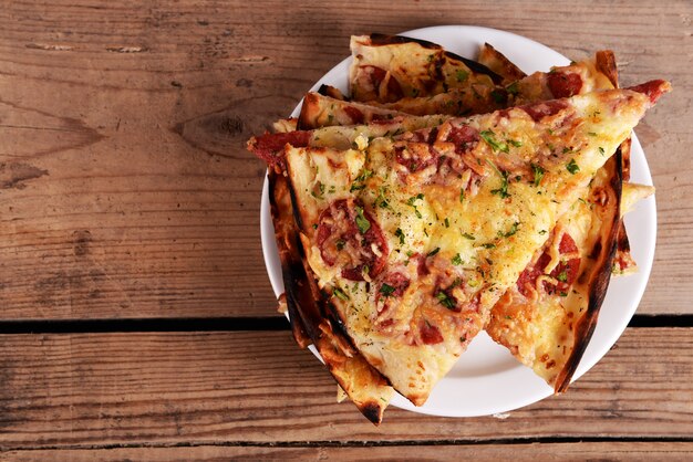 Saborosas fatias de pizza no prato na mesa de madeira