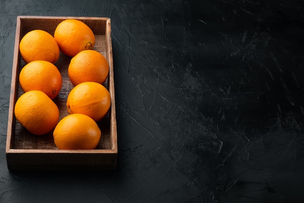 Saborosas laranjas espanholas colhidas na hora, em caixa de madeira, sobre mesa de pedra preta