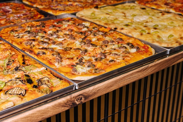 Saborosas pizzas quadradas em bandejas de metal