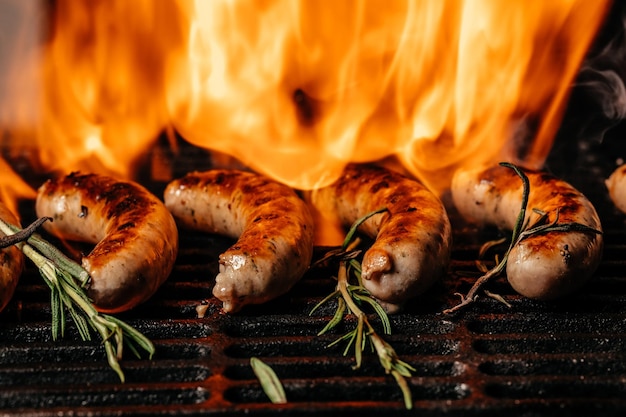 Saborosas salsichas grelhadas na churrasqueira no fogo, grelhadas nas chamas