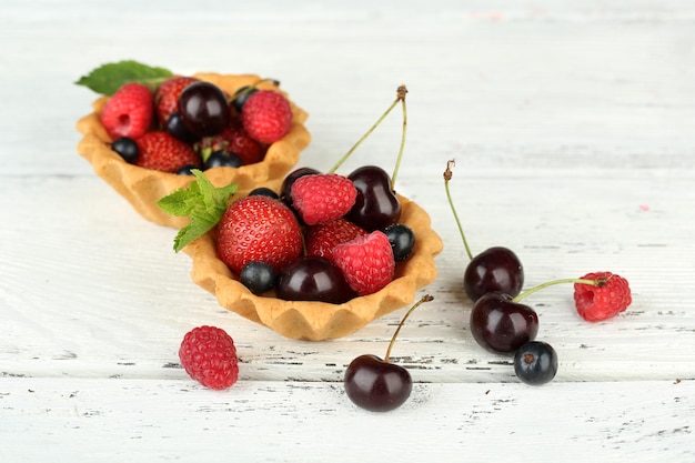 Saborosas tortinhas com frutas na mesa de madeira