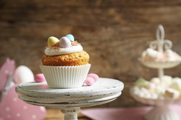 Foto saboroso bolinho de páscoa no suporte do bolo contra uma mesa de madeira