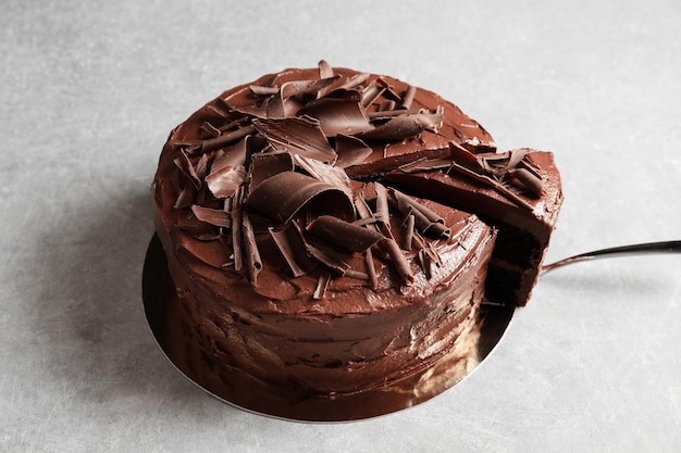 Foto saboroso bolo de chocolate caseiro e pá com pedaço na mesa