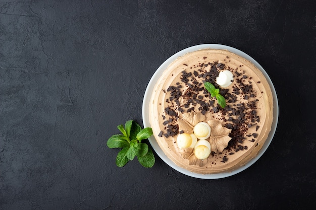 Saboroso bolo decorado com creme e chocolate escuro em fundo preto. Vista superior com espaço de cópia.