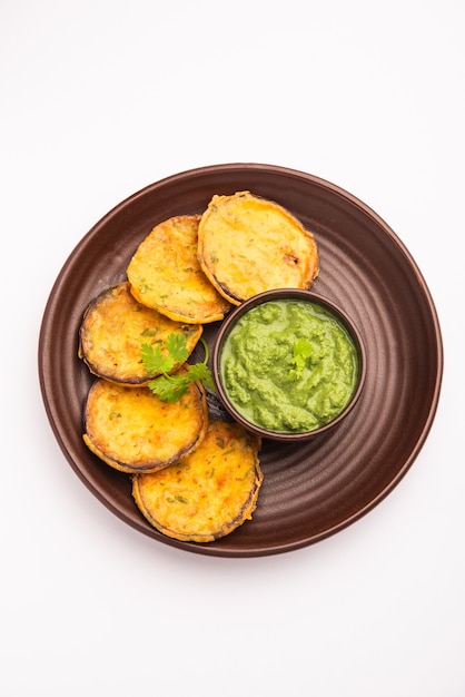 Saboroso brinjal pakora ou bolinhos crocantes de berinjela, lanche da hora do chá indiano servido com chutney verde