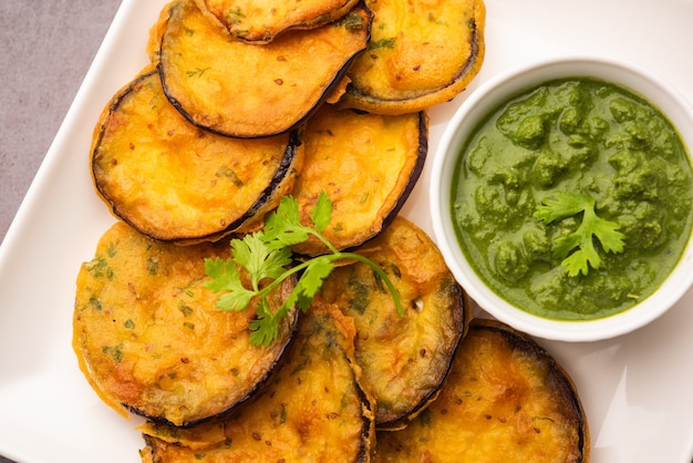 Saboroso brinjal pakora ou bolinhos crocantes de berinjela, lanche da hora do chá indiano servido com chutney verde