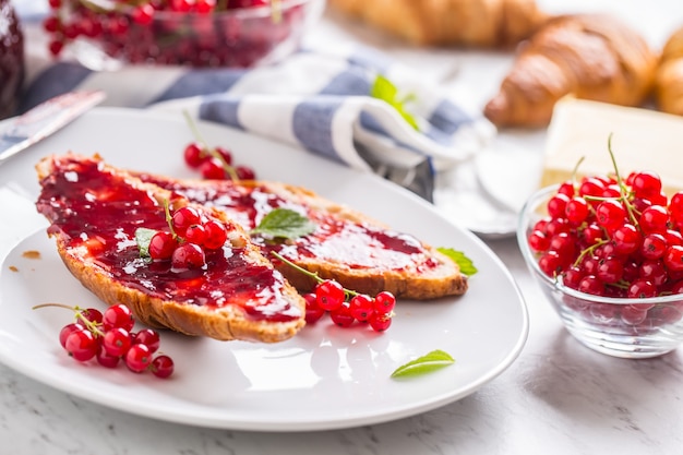 Saboroso café da manhã com croissants de geléia de groselha, manteiga e folhas de hortelã.