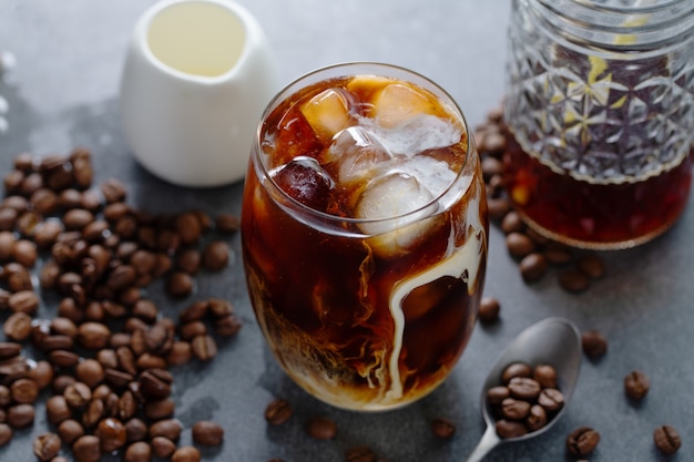 Saboroso café gelado refrescante com cubos de gelo em copos no fundo brilhante. fechar-se