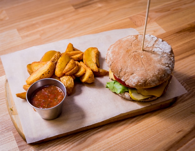 Saboroso cheeseburger e batatas fritas na mesa de madeira. restaurante.