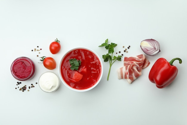 Saboroso comer com borscht e ingredientes na superfície branca