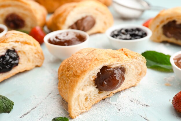 Saboroso croissant com geleia na mesa de luz, closeup