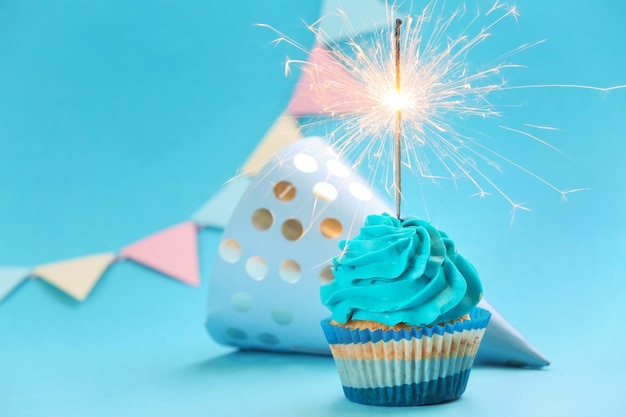 Saboroso cupcake de aniversário com brilho e chapéu de festa em azul