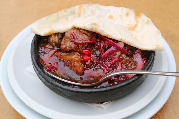 Saboroso ensopado de porco georgiano Kaurma com legumes e ervas