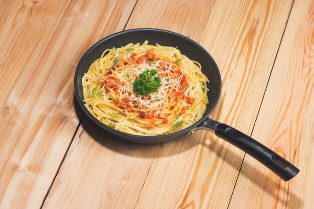 Saboroso espaguete com molho de tomate e carne na panela na mesa de madeira.