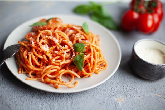 Foto saboroso espaguete italiano clássico com molho de tomate, parmesão e manjericão no prato