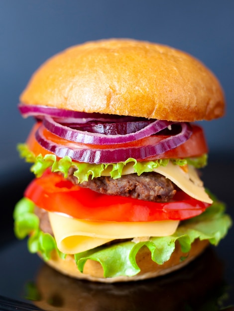 Saboroso hambúrguer com costeleta de carne, salada, queijo, tomate e cebola