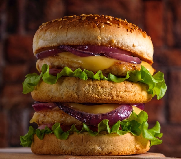 Saboroso hambúrguer grelhado com salada, queijo e cebola, servido em uma tábua de cortar sobre uma mesa de madeira