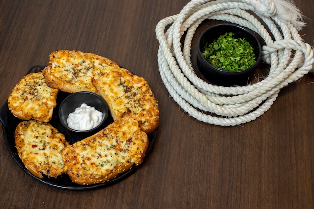 Saboroso pão com alho, queijo e ervas na mesa da cozinha, delicioso pão de alho caseiro