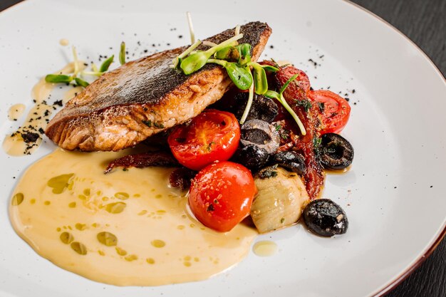 Saboroso peixe dourado grelhado com legumes cozidos e molho em fundo de madeira