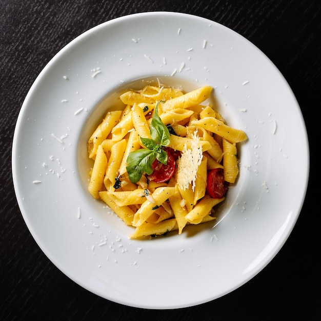 Saboroso prato de macarrão penne com manjericão fresco e queijo em um prato branco