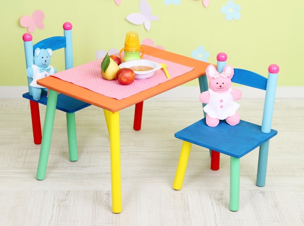 Foto saboroso purê de frutas e mamadeira na mesa do quarto