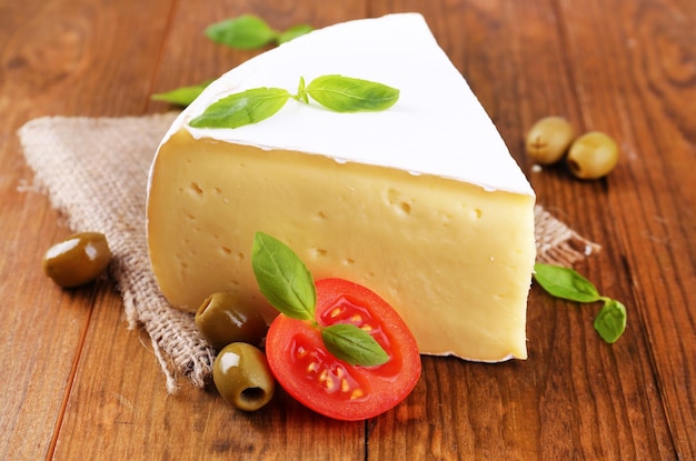 Saboroso queijo Camembert com tomate manjericão e azeitonas na mesa de madeira