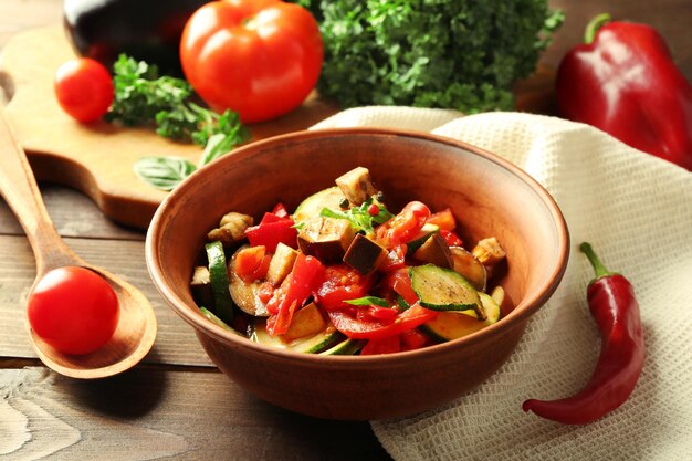 Saboroso ratatouille vegetariano feito de berinjela abóbora tomate em tigela sobre fundo de mesa de madeira