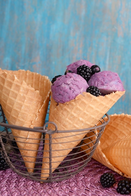 Saboroso sorvete com frutas no cone de waffle no fundo azul de madeira