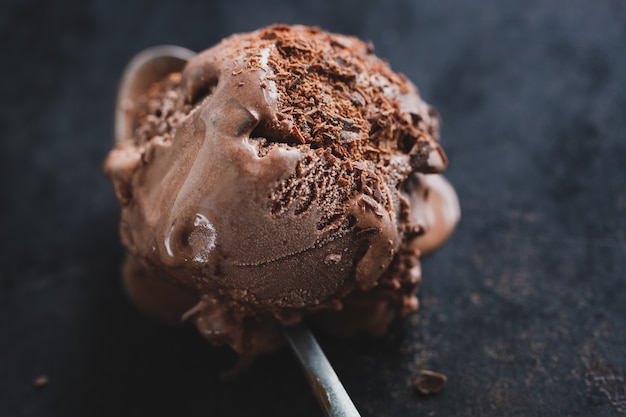 Foto saboroso sorvete de chocolate apetitoso com pedaços de chocolate na chapa escura em fundo escuro.