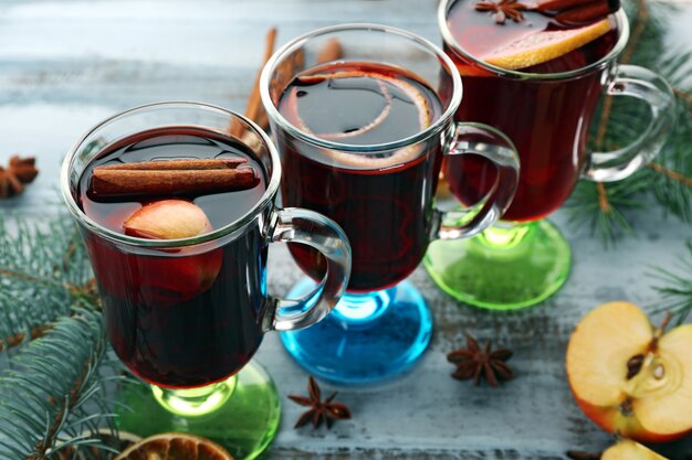 Saboroso vinho quente com especiarias e especiarias, em fundo azul de madeira, close-up