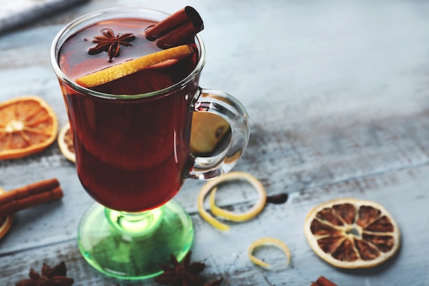 Saboroso vinho quente com especiarias e especiarias, na mesa de madeira azul