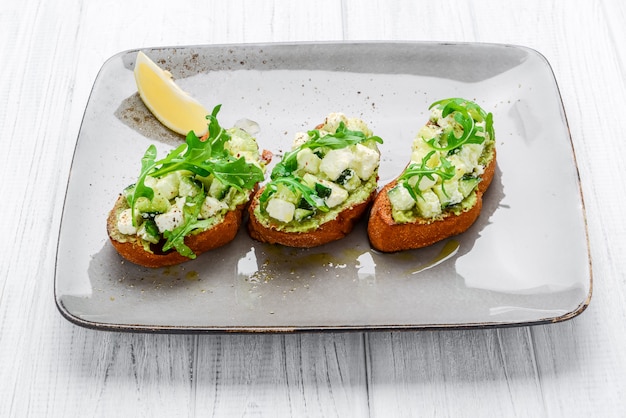 Saborosos aperitivos italianos salgados, ou bruschetta, em fatias de baguete tostada, guarnecidas com manjericão