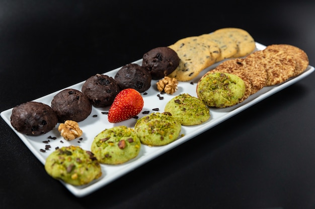 Saborosos biscoitos de chocolate coloridos no fundo preto
