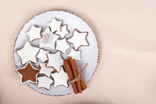 Saborosos biscoitos pintados com estrelas e paus de canela no prato de vista superior Gingerbread