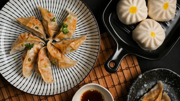 Saborosos bolinhos chineses cozidos no vapor ou bolinhos gyoza japoneses com um prato de pãezinhos de porco na mesa