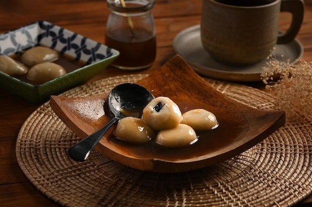 Saborosos bolinhos de arroz com sopa de gengibre em prato de madeira.