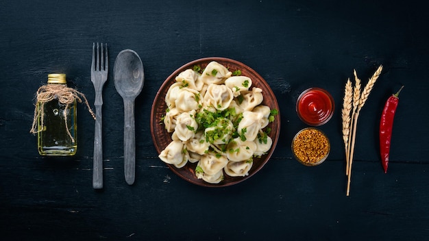 Saborosos bolinhos de carne caseiros de farinha integral ou pelmeni russo polvilhado com salsa fresca no prato na mesa de madeiracopy espaço vista de cima